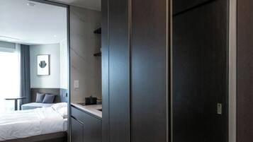 Habitación de hotel moderna con cama, escritorio, armario y vista de la habitación contigua.