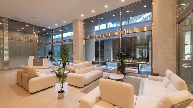 Eine moderne Lobby mit einer Rezeption, einer Sitzecke und großen Fenstern.