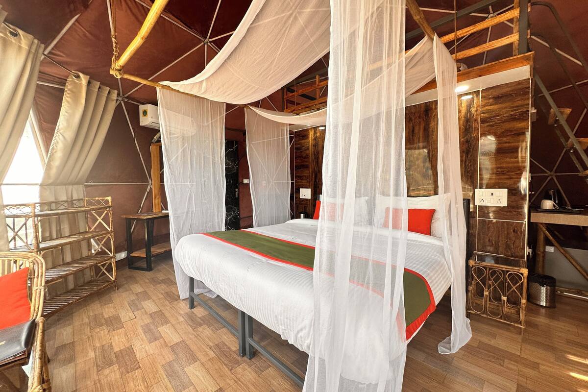 Una habitación con cama bajo un dosel, suelo de madera y decoración de estilo rústico.