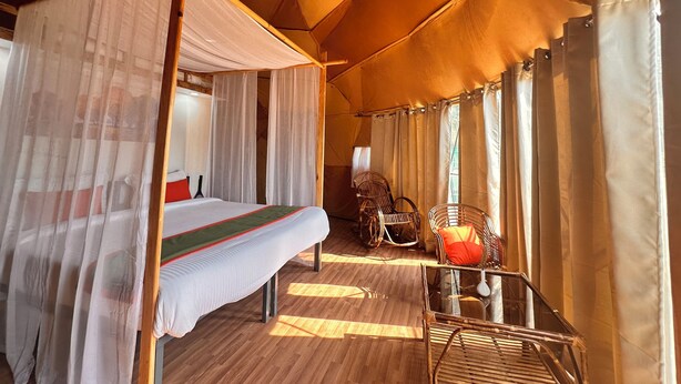 A tented room with a bed, a glass table, wicker chairs, and a canopy bed. - Nestonature Glamping Dharamshala (Dharamshala)
