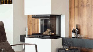 Un saló modern amb una llar de foc, un sofà, una taula de centre amb objectes decoratius i una paret d'accent de fusta.