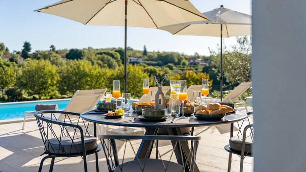 Une table à manger avec des chaises, une piscine et une vue sur la campagne.