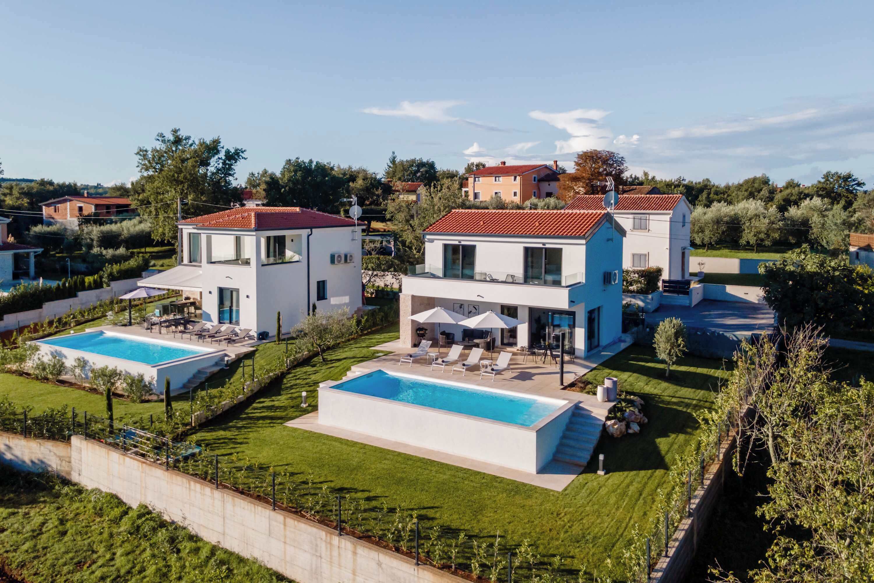 Ein modernes, zweistöckiges Haus mit Swimmingpool, gepflegtem Rasen und Blick auf die Umgebung.