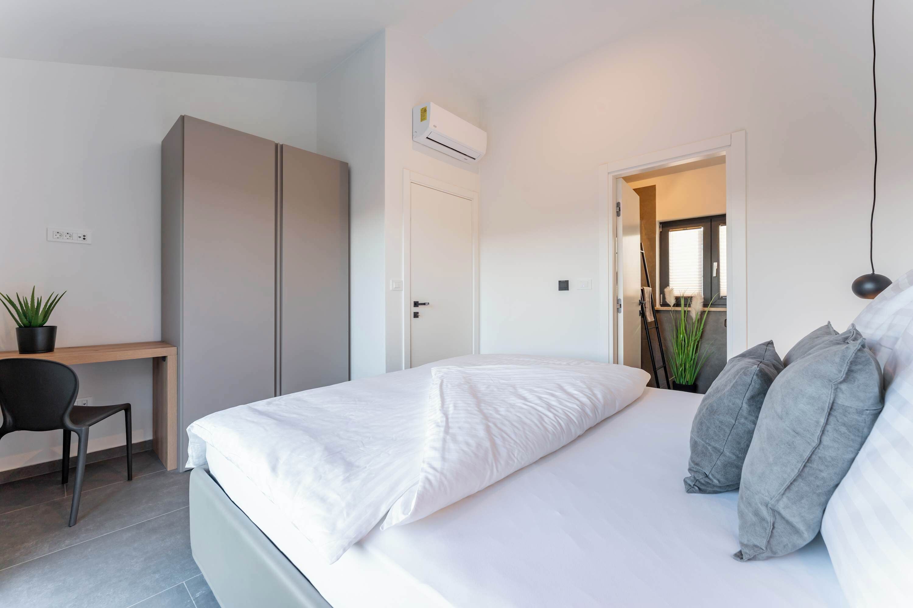 Ein Schlafzimmer mit Bett, Schreibtisch, Stuhl und Klimaanlage.