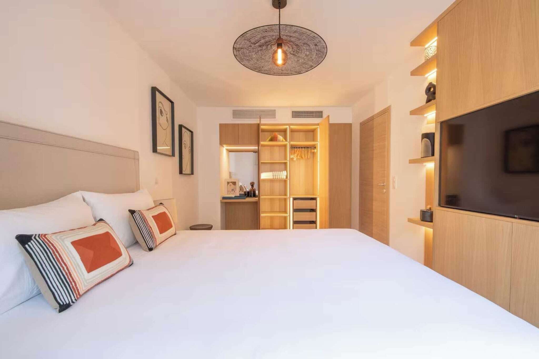 Una habitación de hotel con una cama grande, un televisor, un armario y un vestidor.