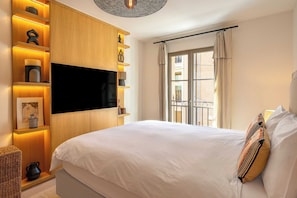 A hotel room with a bed, a TV mounted on the wall, a window with a view, and a curtain.