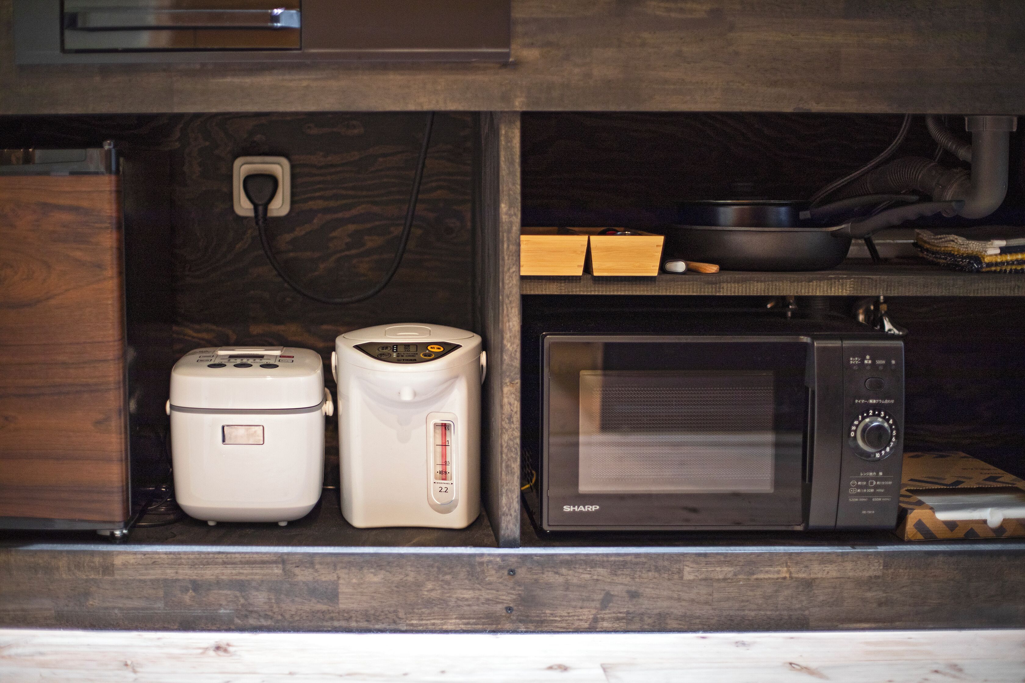 A kitchen with a microwave, a rice cooker, and a toaster.