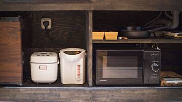 A kitchen with a microwave, a rice cooker, and a toaster.