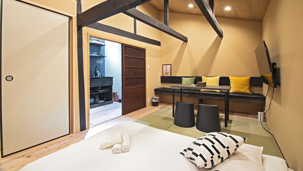 Un dormitorio con cama, sofá, televisor y estructura de techo de madera.