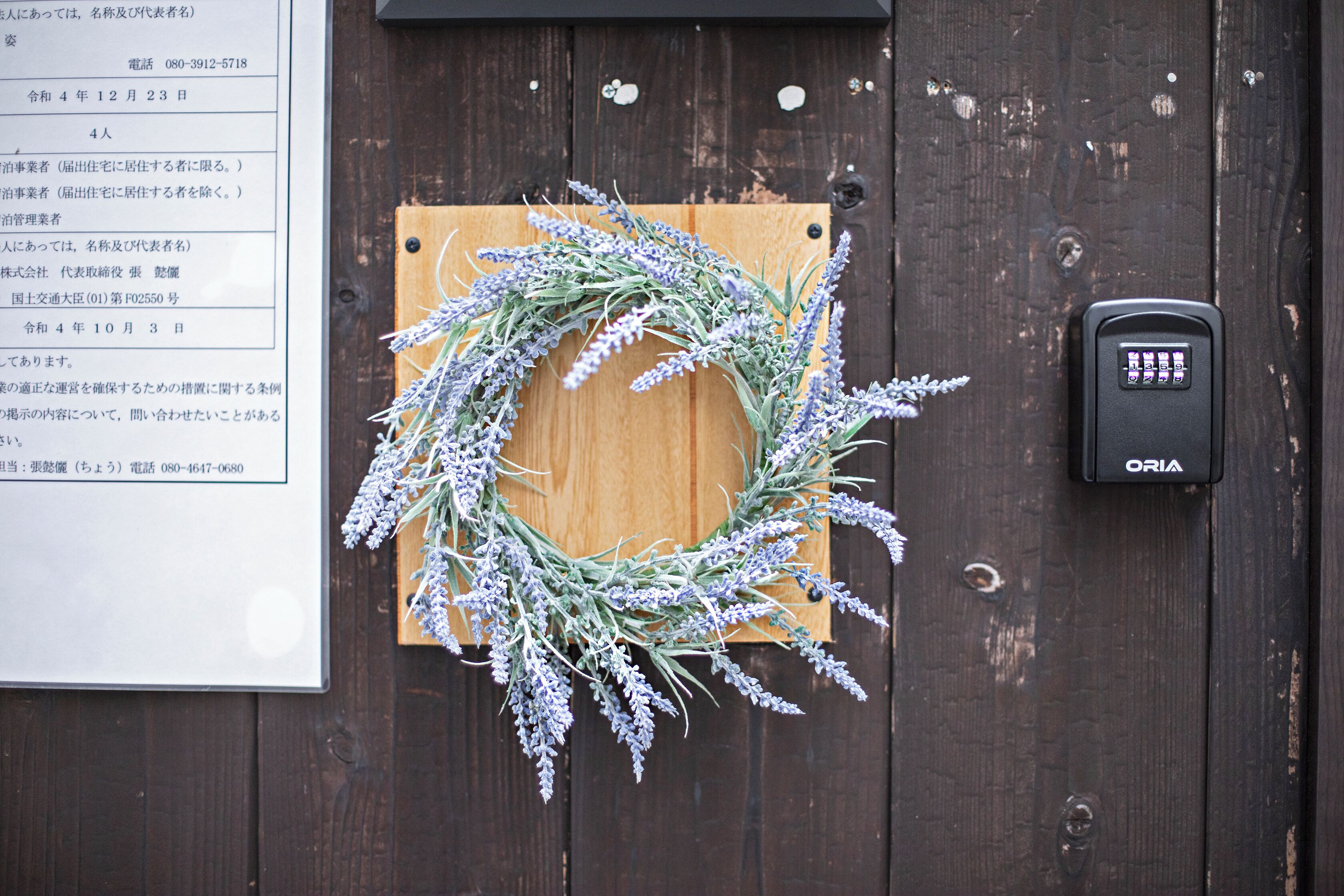 Una porta in legno con una tastiera di sicurezza e una ghirlanda di lavanda.