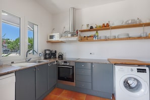 A compact kitchen with a sink, stove, microwave, and a washing machine. - Villa 'Agua Turquesa' with Private Pool, Wi-Fi and Air Conditioning (Sant Lluís)