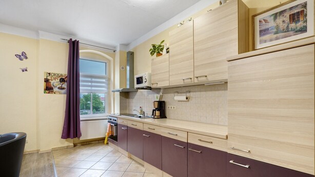 Una cocina con ventana, armarios, microondas y pileta.