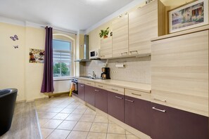 Une cuisine avec une fenêtre, des placards, un four à micro-ondes et un évier.