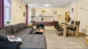 Un espacio de sala con un sofá, una mesa de comedor con sillas, una cocina al fondo y adhesivos de pared con mariposas.