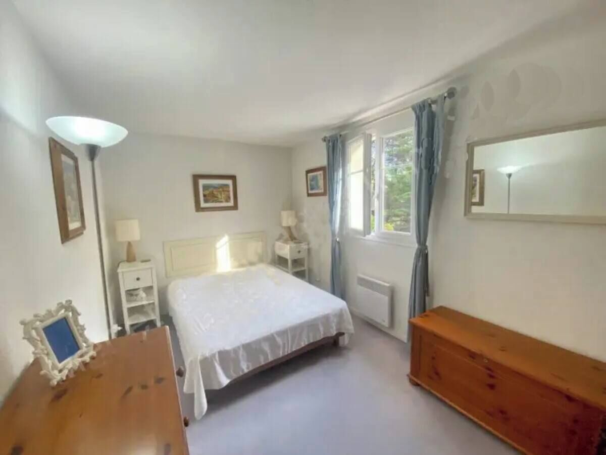 Ein Schlafzimmer mit Bett, Nachttischen, einem Schminktisch, einem Spiegel und einem Fenster mit Vorhängen.