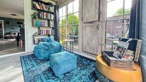 Un salon chaleureux avec une grande bibliothèque, un canapé bleu et un tapis à motifs.