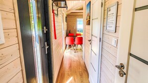 A corridor with wooden walls, a door with a metal handle, and a window with a view of greenery.