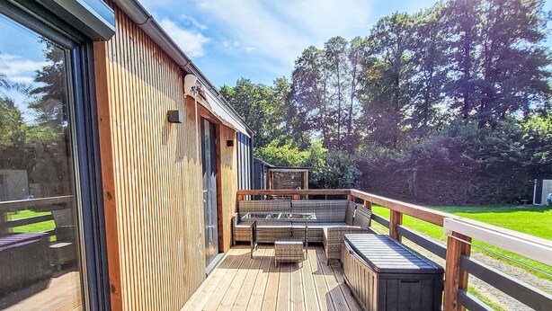 A wooden deck with outdoor seating and a view of a green landscape.