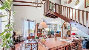 Un salon spacieux avec un escalier en bois, un grand bureau en bois et divers objets décoratifs.