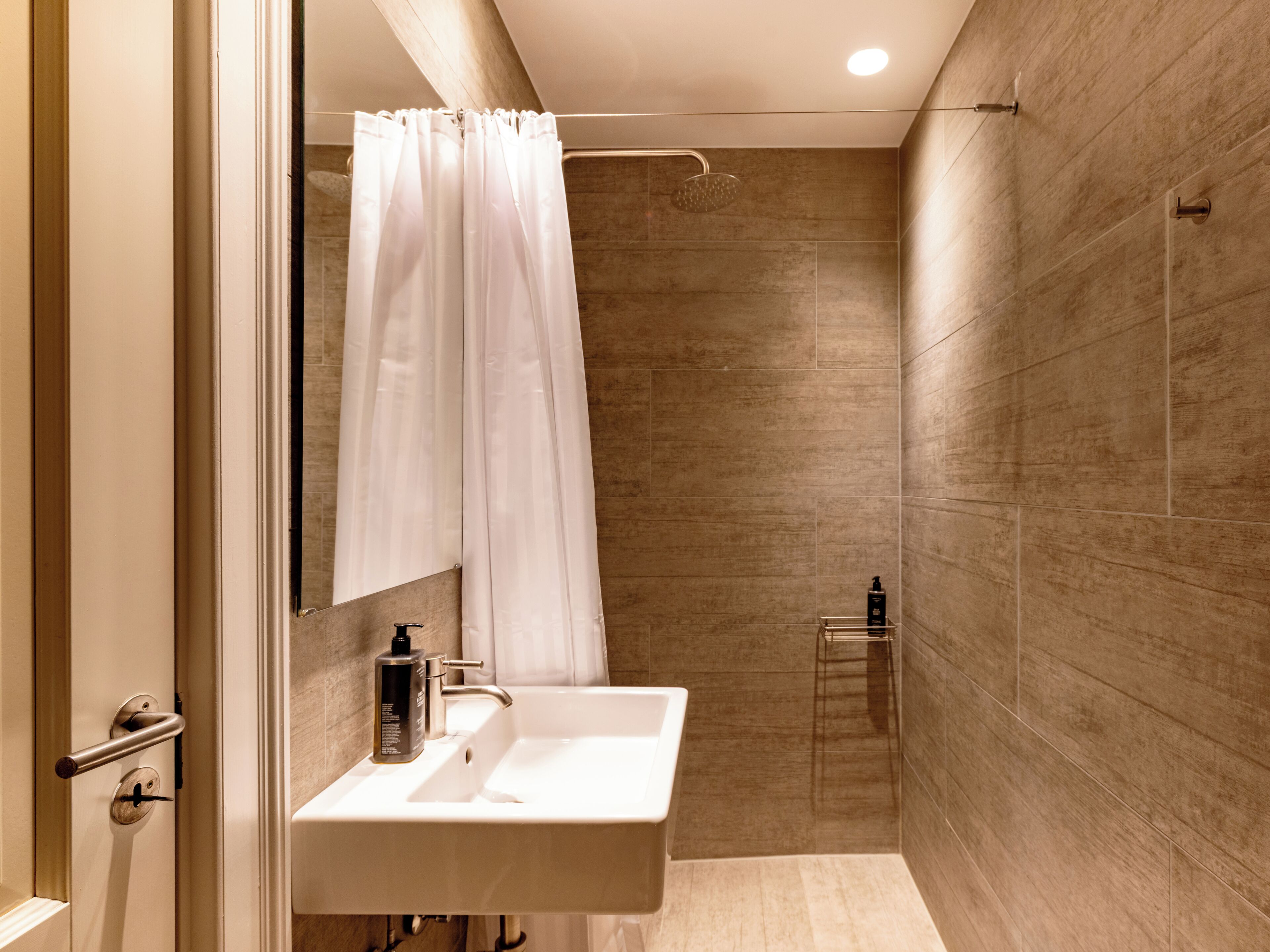 Une salle de bain moderne équipée d’une douche, d’un lavabo et d’un miroir.