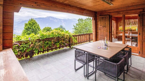 A wooden deck with a table and chairs, a view of mountains, and a wooden door. - Champ de Brent by Interhome (Ollon)
