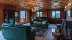 A spacious living room with a green sofa set, a coffee table, and a chandelier. - Champ de Brent by Interhome (Ollon)