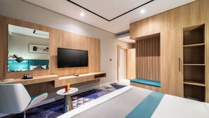 Una habitación de hotel moderna con una cama, un escritorio con silla, un televisor montado en la pared y un armario.