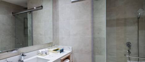 A modern bathroom with a glass shower enclosure, a large mirror, and a marble sink.