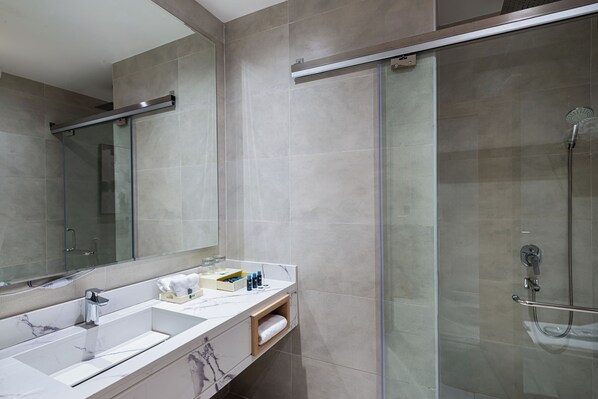 A modern bathroom with a glass shower enclosure, a large mirror, and a marble sink. - Rhenium Jazan (Jizan)