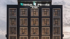 Un moderno edificio de hotel con una señalización destacada que dice 'Henium Hotels & Resorts By AlQaisar'.