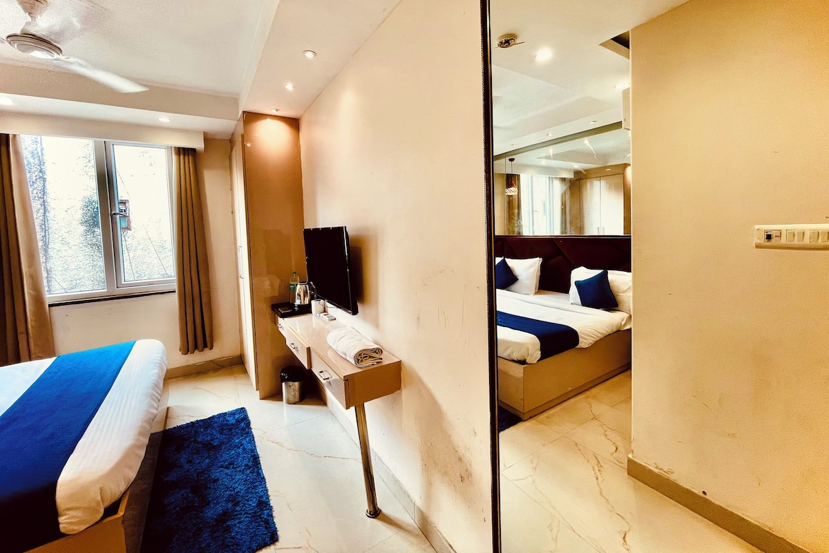 A hotel room with a bed, bedside table, and a mirror.