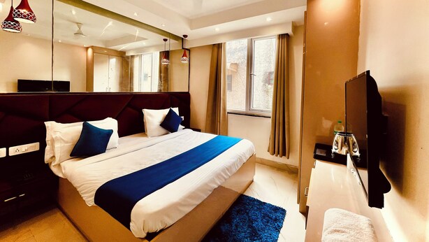 Une chambre d’hôtel moderne dotée d’un grand lit, d’un téléviseur à écran plat, d’un ventilateur de plafond et d’une fenêtre avec des rideaux.