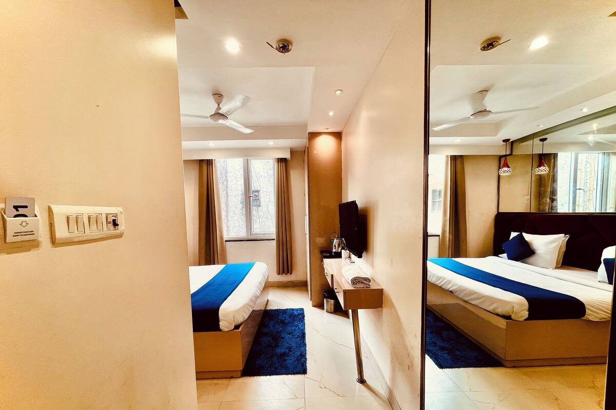 A hotel room with a bed, a desk, a mirror, and a ceiling fan.