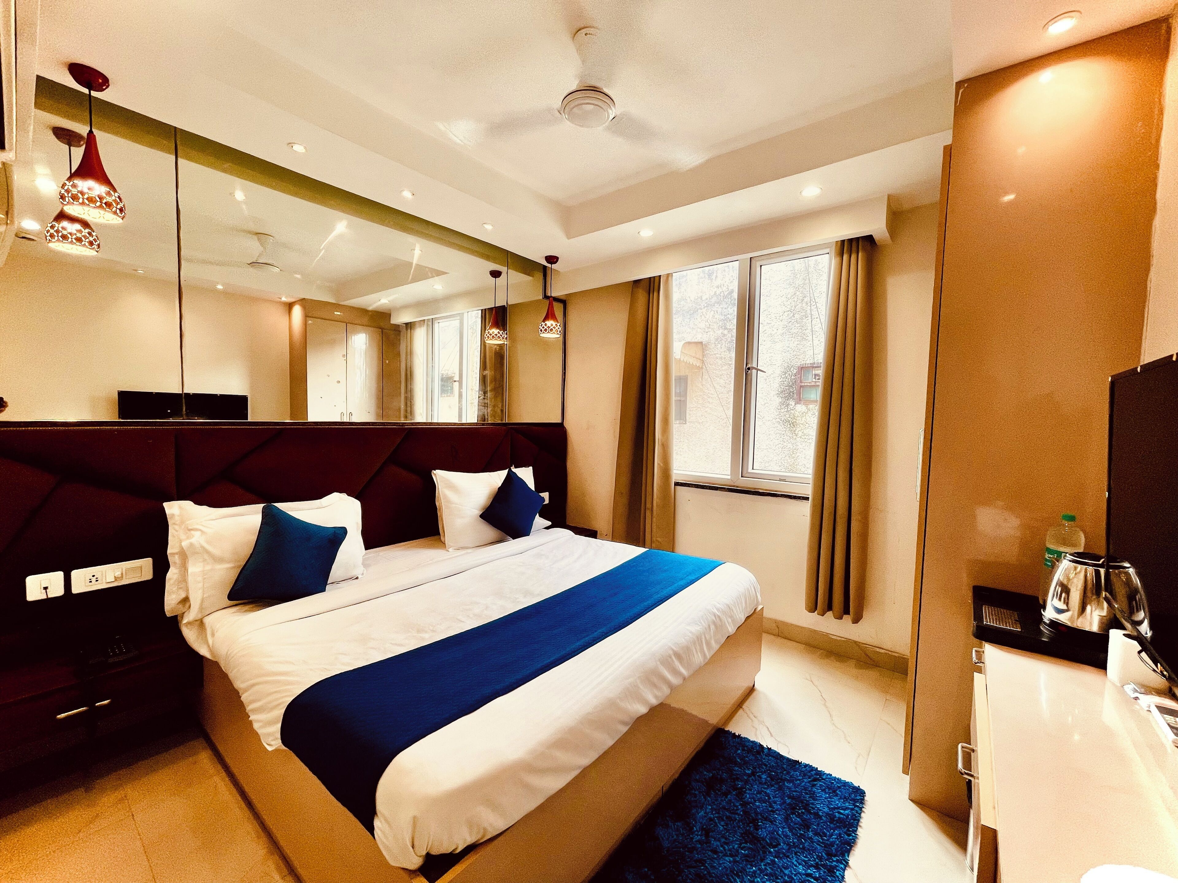 Una habitación de hotel moderna con una cama grande, un televisor de pantalla plana, un escritorio y un ventanal con cortinas.