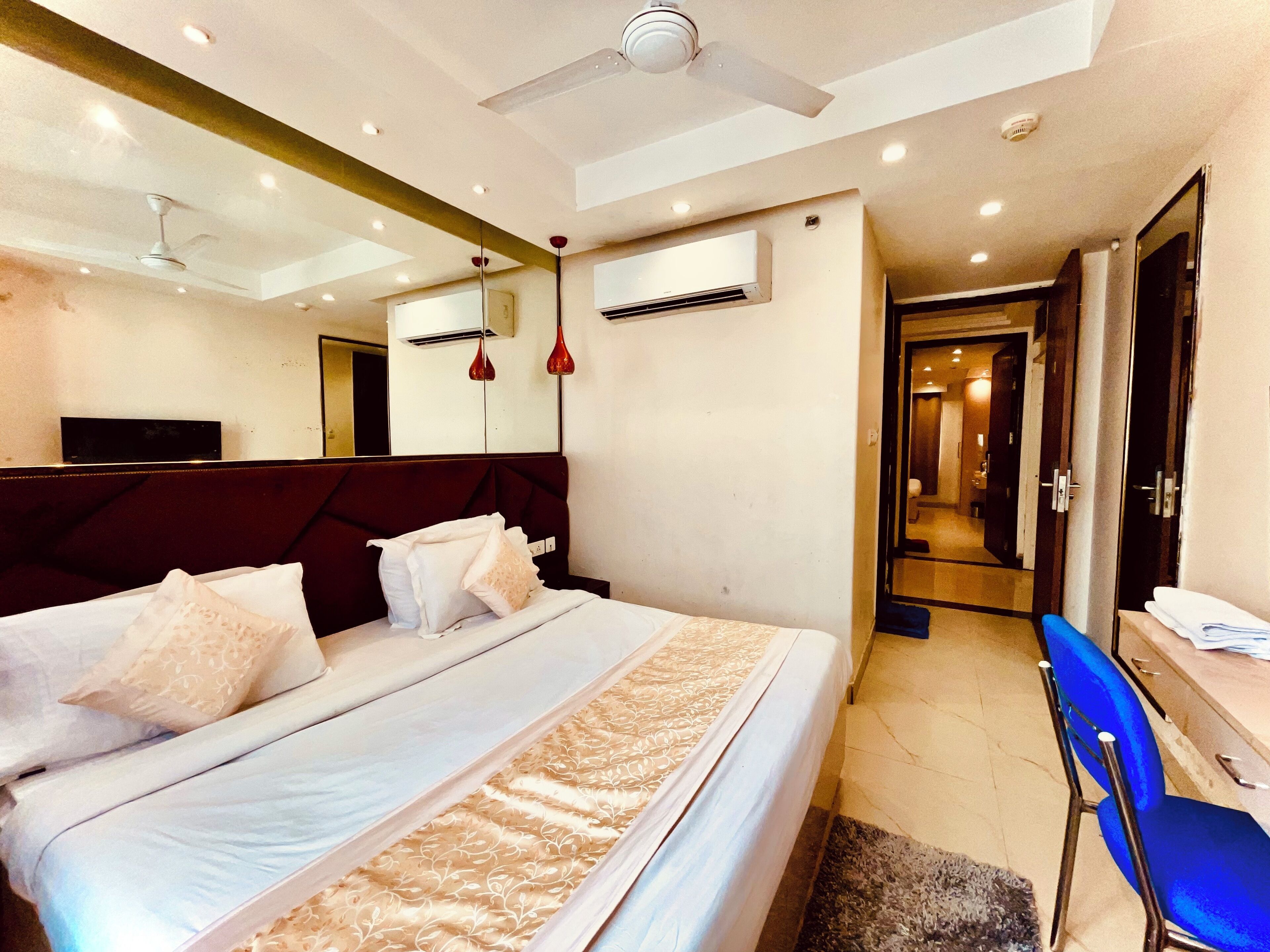 Quarto de hotel moderno com uma cama grande, uma escrivaninha, uma cadeira e um ventilador de teto.