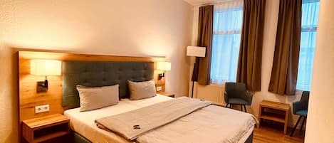 Une chambre d’hôtel avec un grand lit, des lampes de chevet, un bureau et une chaise.