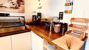 A modern kitchen with a wooden countertop, a coffee machine, and a wall-mounted light fixture. - Haus Borkum (Borkum)
