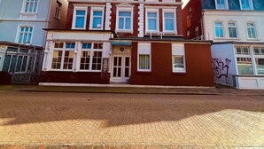 A multi-story building with a brick facade, large windows, and a visible storefront. - Haus Borkum (Borkum)