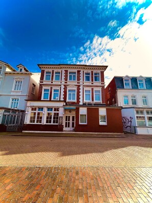 A multi-story building with a brick facade, large windows, and a visible storefront. - Haus Borkum (Borkum)