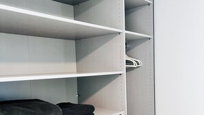 A closet with open shelves and a hanging rod, featuring a folded towel on the bottom shelf.