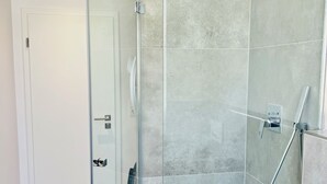A modern bathroom with a glass shower enclosure, a white sink, and a towel rack. - Stylish 1-room apartment + terrace (Herzogenaurach)