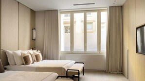 A hotel room with two beds, a large window with curtains, a flat-screen TV, and a wall-mounted light fixture. - Luxury Flat -2br/8p- Madeleine/saint Honore (Paris)