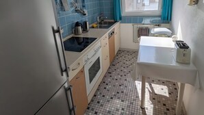 Eine kleine Küche mit Kühlschrank, Herd, Spüle und einem Tisch mit Toaster.
