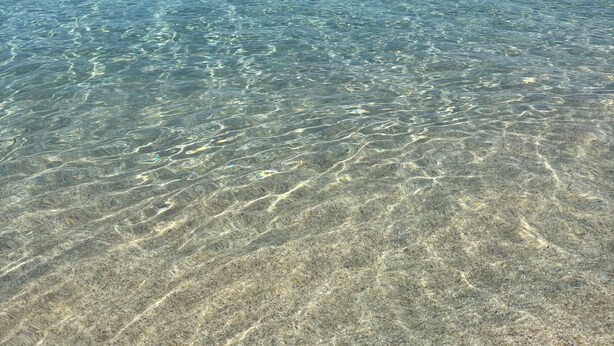 Eau claire et peu profonde, où l’on peut distinguer les motifs formés par le sable.