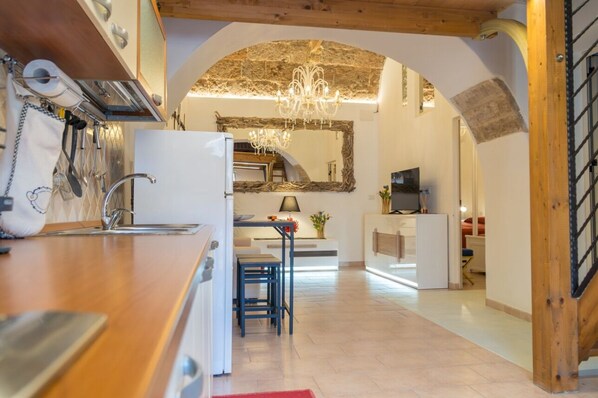Une cuisine moderne avec un plan de travail en bois, un évier et un lustre. On y trouve également un coin repas avec une table et des chaises.
