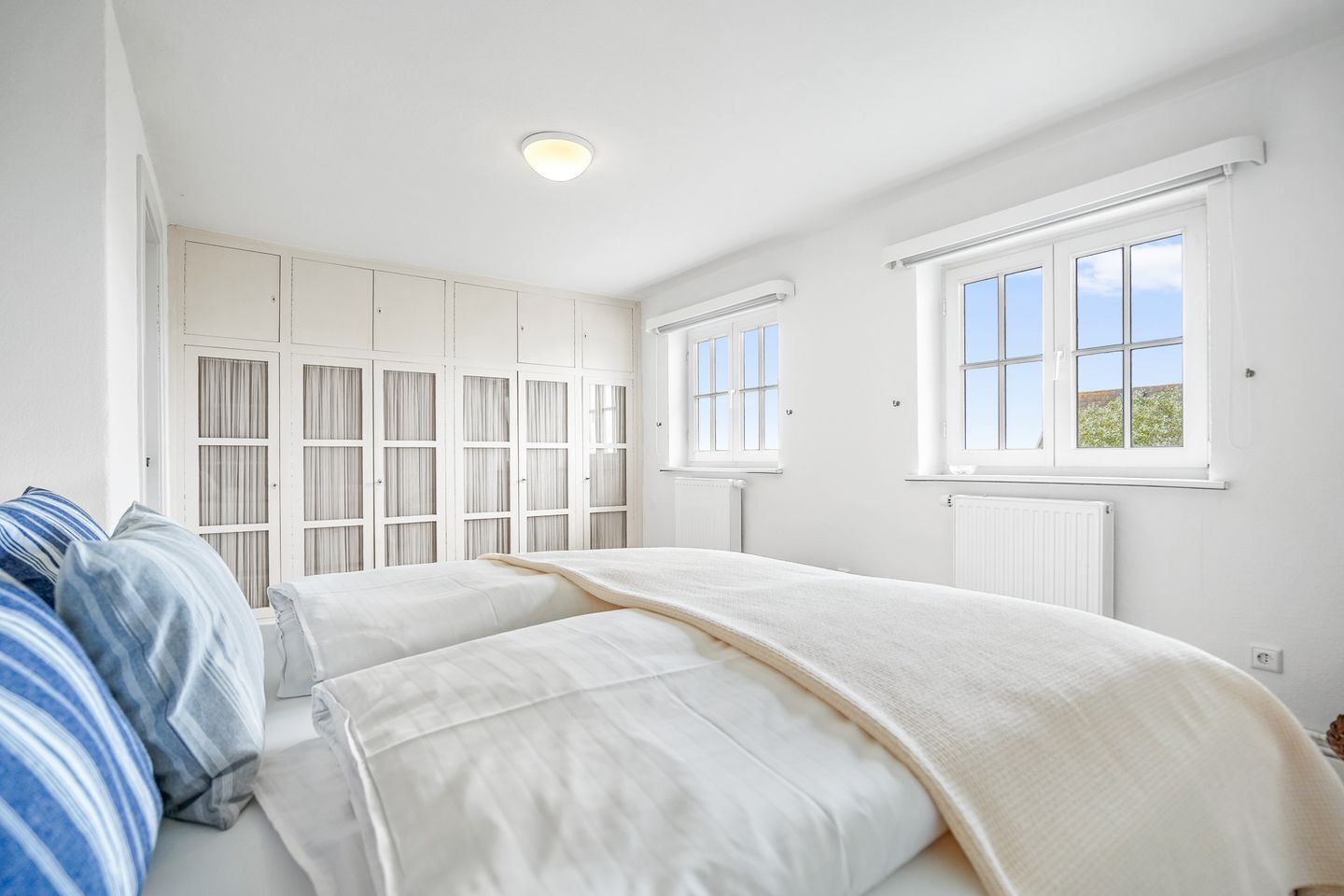 Un dormitorio con cama, armario y ventana.