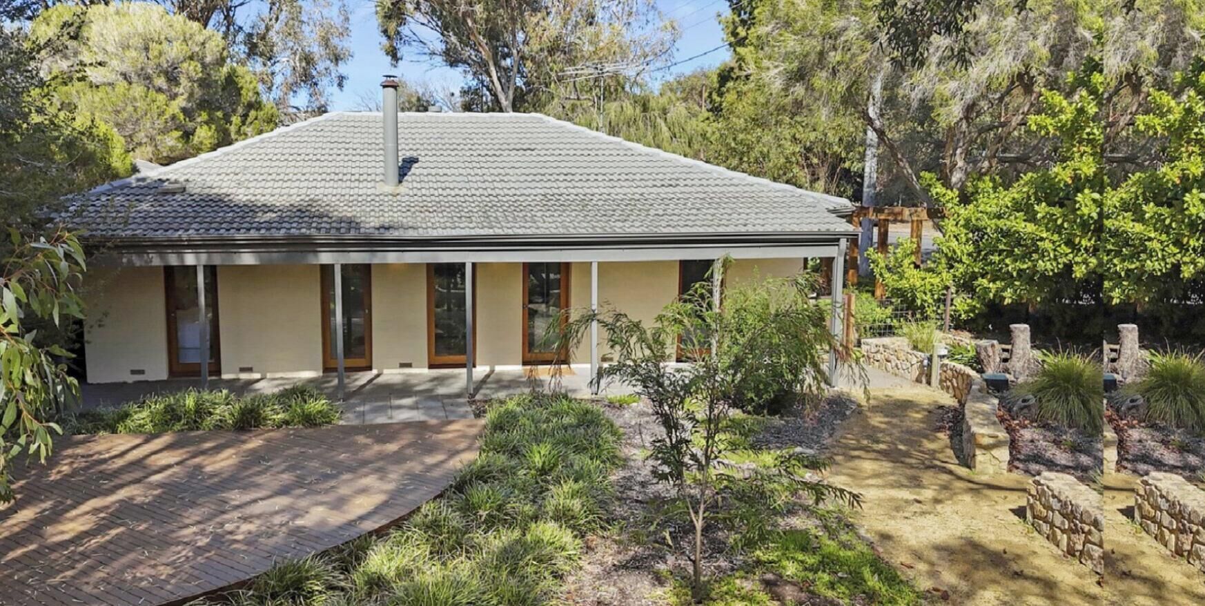A single-story house with a tiled roof, a front porch, and a pathway leading to the entrance.