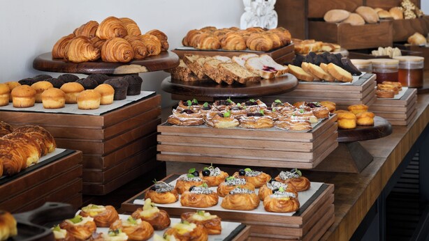 A variety of pastries and baked goods displayed on wooden stands and trays. - Palace Beach Resort (El Alamein)