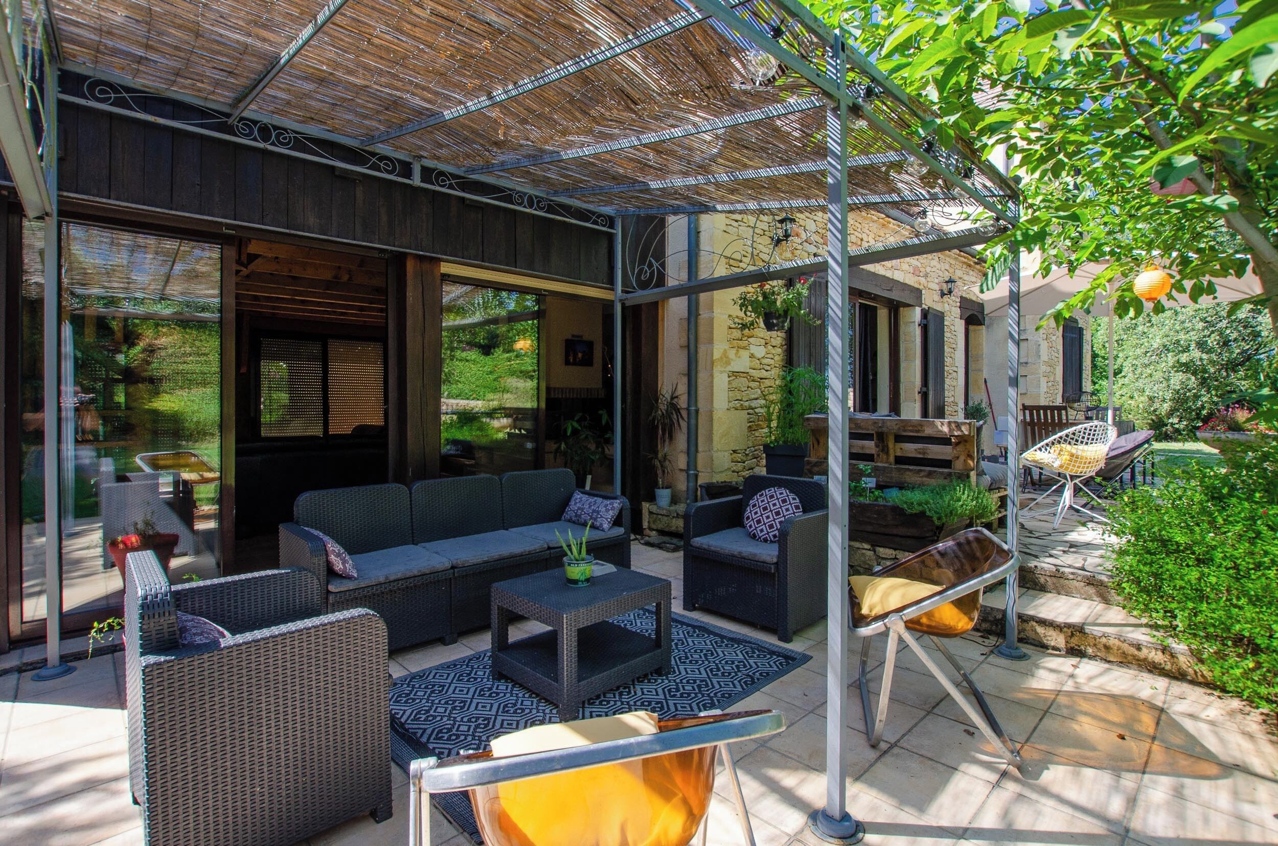 An outdoor patio with wicker furniture, a fire pit, and a pergola structure.