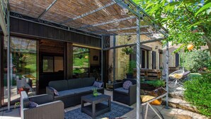 Un patio exterior con mobiliario de mimbre, un hogar para fogata y una estructura de pérgola.